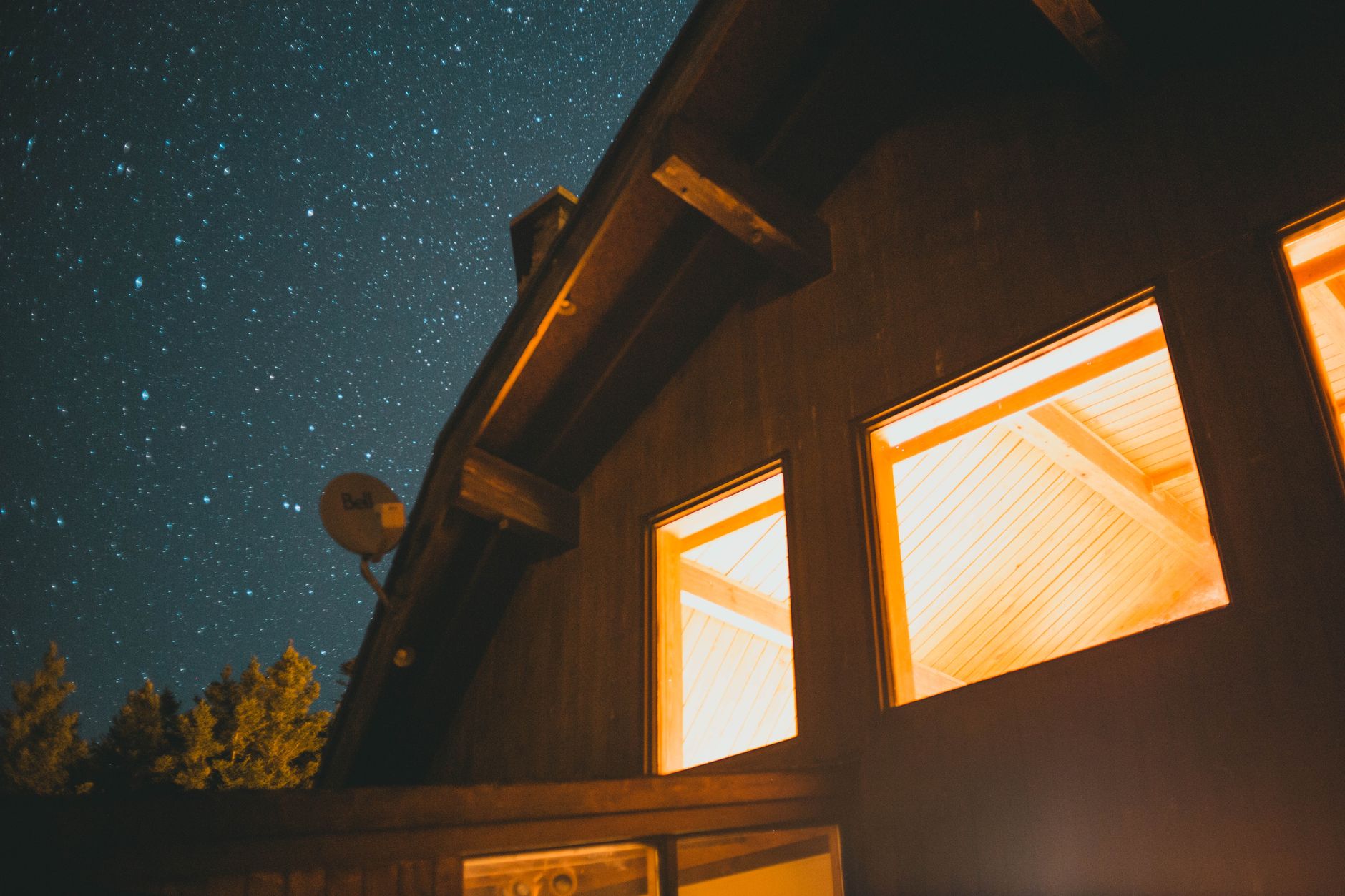 Verlichte woning bij nacht onder een sterrenhemel